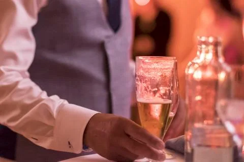 Close up of hand of waiter serving a bottle with a glass of champagne or wine Stock Photos