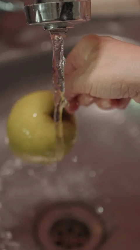 Close up of hand washing green apples under running water in kitchen sink with Stock Footage 344410745
