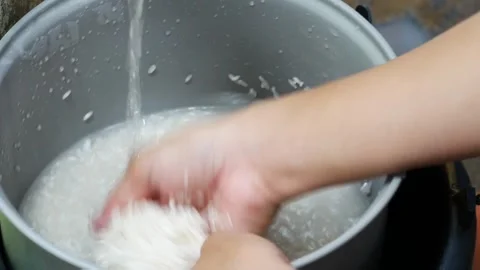 Close-up of hand washing raw white rice in a metal pot Stockbeeldmateriaal 333443239