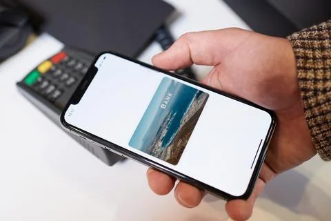 A close-up hand which is holding a smartphone while paying using NFC in a sto Stock Photos