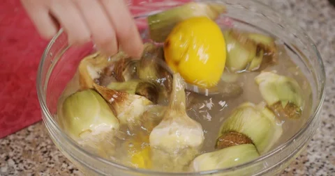 Close up of hand while mixes artichokes and lemon in a cup of water Stock Footage 128958267