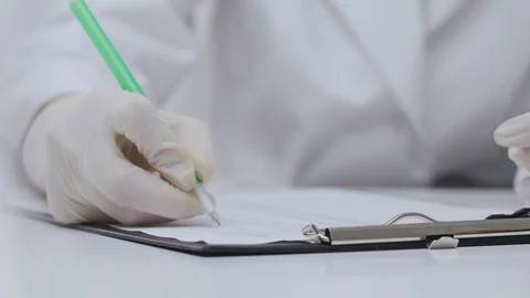 Close-up of hand in white gloves mark with pen in sheet Stock Footage 129855710