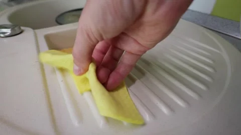 Close Up of Hand Wiping Beige Kitchen Sink Surface with Yellow Cleaning Cloth Stock Footage 339215828