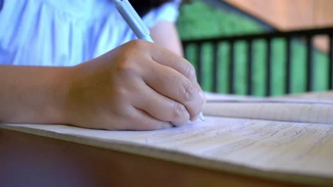 Close up hand of woman sitting at desk holding pen making notes in a book Stock Footage 222024916