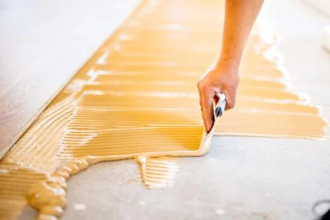 Close-up of hand of worker adding glue during parquet installation Stock Photos