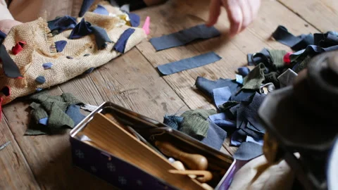 Close-up of hand working with textile pieces on a wooden table, alongside Stock Footage 271535846