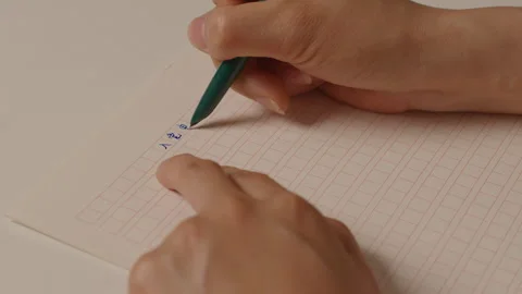 Close-up of Hand Writing Asian Characters on Grid Paper Vídeos de archivo 335478175