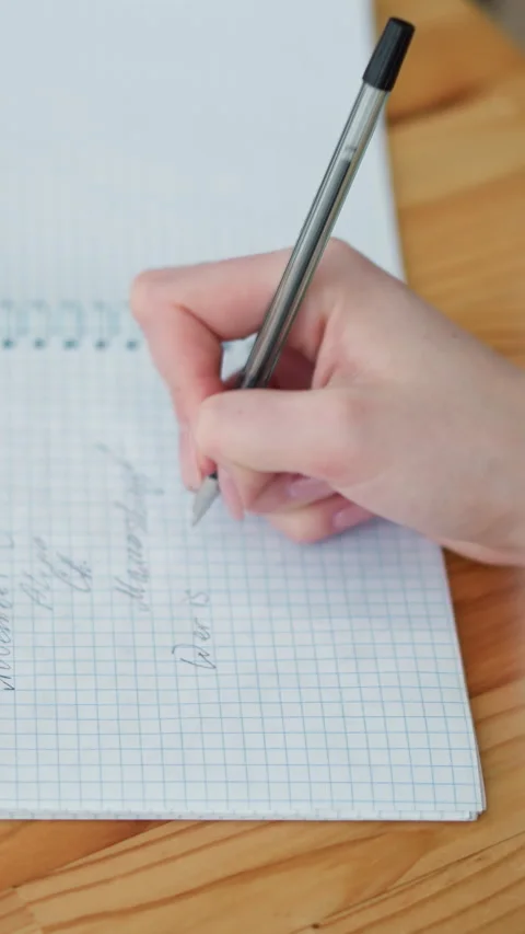 Close-up hand writing with black pen on notebook with coffee cup on wooden table Stockbeeldmateriaal 318224669