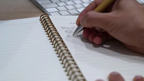 Close-up hand writing content calendar planning notes in spiral notebook on Stock Footage 332120683