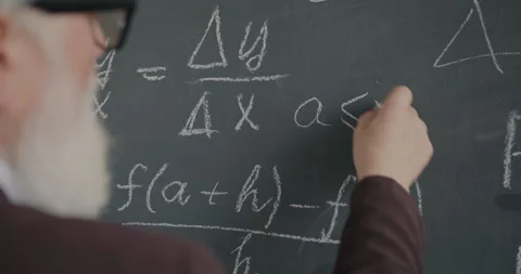 Close-up of hand writing formula on chalkboard while senior man professor doing Stock Footage 281145629