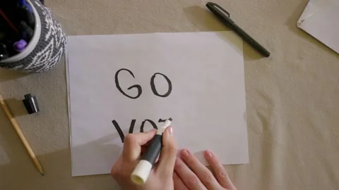 Close up of hand writing go vote on a piece of paper with a sharpie. Stock Footage 142845976