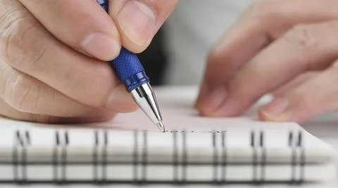 Close up hand writing paper on notebook with pen at office desk Stock Photos