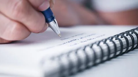Close up hand writing paper on notebook with pen at office desk Stock Photos