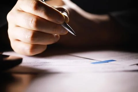 Close-Up of Hand Writing with Pen on Documents under Focused Light Stock Photos