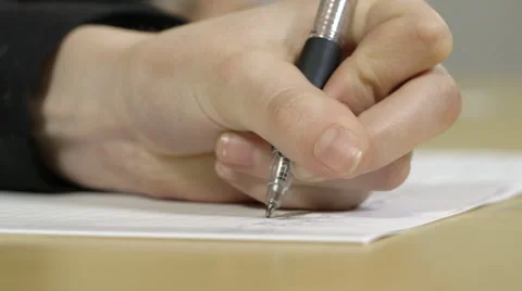 Close up of a hand writing with pen in exam or classroom setting, shallow focus Stock-Footage 66547432