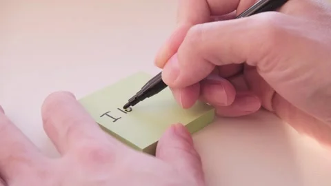 Close-up of hand writing the phrase I love you on a paper sticker. Video footage Stock Footage 335553126