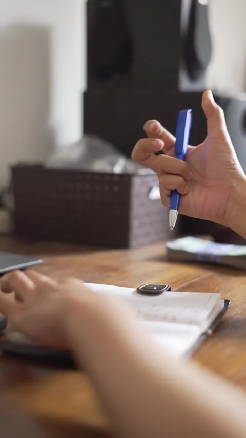 Close up of a hand writing in a small book using blue pen in vertical video Stock Footage 255819778