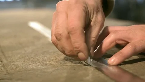 Close-up hand of a young blacksmith who draws a chalk line on the table with a Stock Footage 76362447