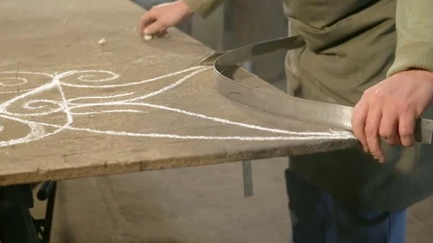 Close-up hand of a young blacksmith who draws a chalk line on the table with a Stock Footage 76362807