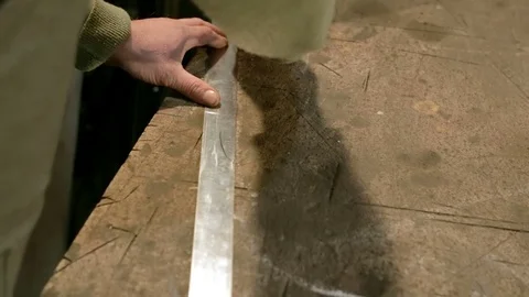 Close-up hand of a young blacksmith who draws a chalk line on the table with a Stock Footage 76411014