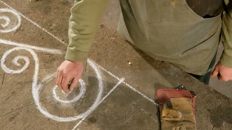 Close-up hand of a young blacksmith who draws a chalk sketch on the table Stock Footage 77004250