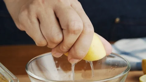 Close-up Hand of young clean chef squeeze the lemon into a glass bowl Stock Footage 115259866