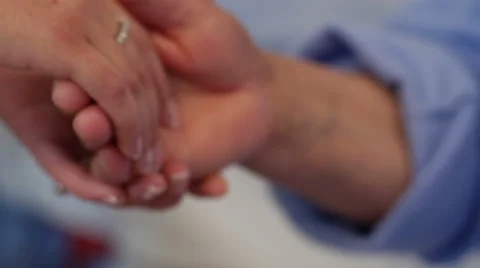 Close up of a hand of a young nurse or doctor holding an old hand of a patient Stock Footage 68684787