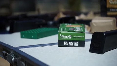 A close-up handheld camera shot showing gold bullets dropping onto a table. Stock Footage 196309924