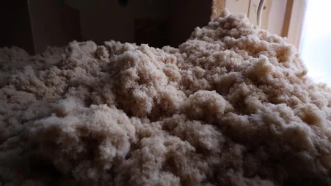 Close up handheld push over beige blown in insulation in attic Stock Footage 337583677