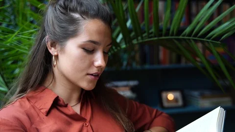 Close-up handheld shot of attractive young woman reading book in slow motion Stock Footage 114883484