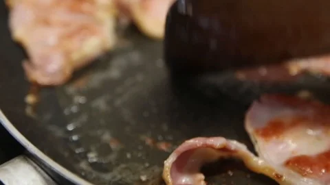A close up handheld shot of bacon in a frying pan Stock Footage 87857052