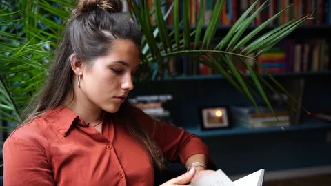 Close-up handheld shot of beautiful young woman reading book in slow motion Vídeo Stock 114883480