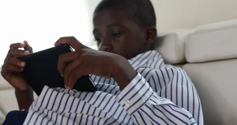 Close-up handheld shot of boy sitting on sofa and looking at digital tablet Stock Footage 119797887