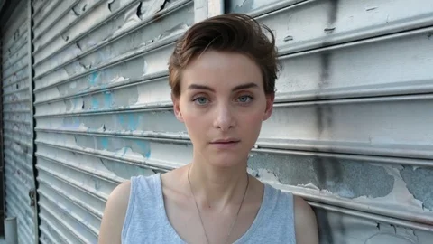 Close-up handheld shot of confident young woman leaning on closed shutter Stock Footage 114862414