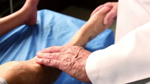 CLOSE UP-HANDHELD SHOT. Doctor's hands touching a patient leg during a check up. Stock Footage 48500240