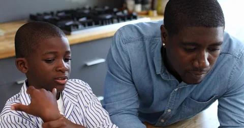 Close-up handheld shot of father teaching son to use laptop in kitchen Stock Footage 119795361