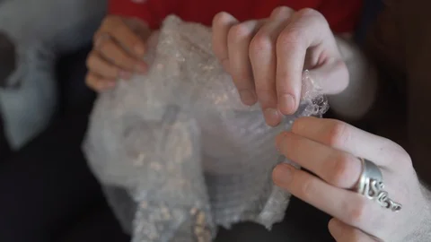 Close-up handheld shot of friends playing with bubble wrap plastic Stock Footage 120430989