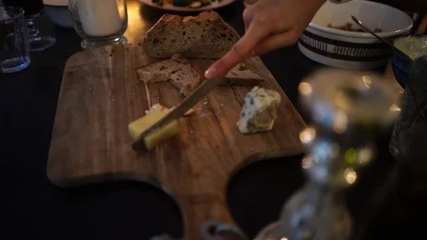 Close-up handheld shot of hand cutting butter with knife on cutting board Stock Footage 114883717