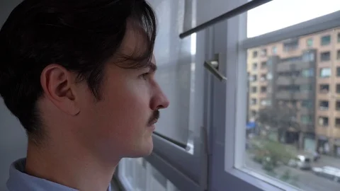 Close-up handheld shot of handsome man with moustache looking through window 스톡 동영상 114871866