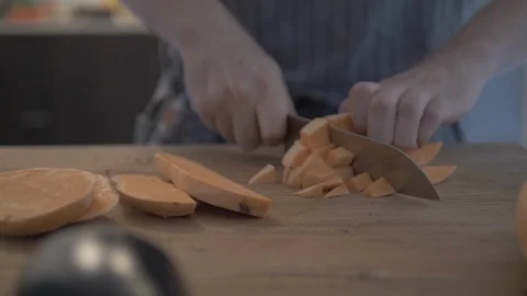 Close-up handheld shot of man cutting sweet potato on cutting board Vídeo Stock 114842334