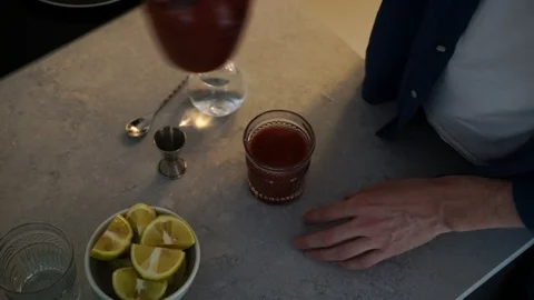 Close-up handheld shot of man squeezing lemon in the drink Stock Footage 114884565
