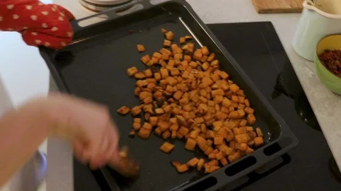 Close-up handheld shot mans hand stirring potato pieces in roasting pan Vídeo Stock 114867323