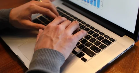 Close-up handheld shot of mans hand typing on laptop over the wooden table Stock Footage 119841148