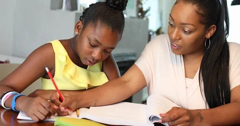 Close-up handheld shot of mother and daughter doing homework in their kitchen Video stock 119753653