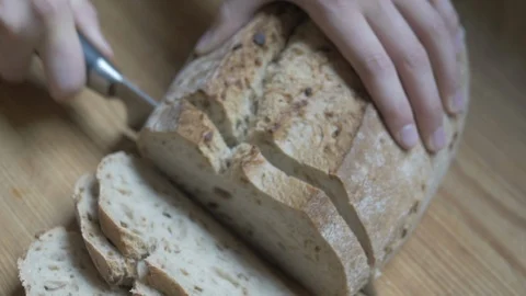 Close-up handheld shot of persons hand cutting fresh loaf of bread Video stock 114842135