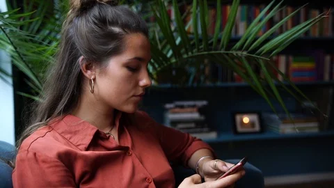 Close-up handheld shot of pretty young woman smiling while using smartphone Stock-Footage 114883499