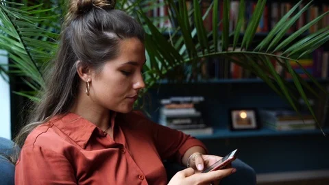 Close-up handheld shot of smiling young woman using smartphone in slow motion Video stock 114883488