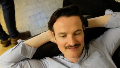 Close-up handheld shot of smiling young man lying on sofa during break time Stock-Footage 120429958