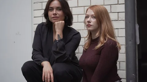 Close-up handheld shot of two young woman posing against brick wall Stock Footage 114877939