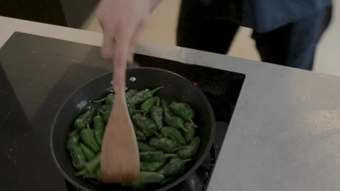 Close-up handheld shot womans hand stirring chilli peppers in pan Stock Footage 114866938